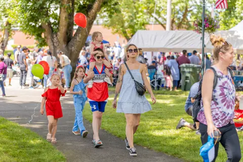 People walking along a path at an outdoor community event with balloons.
