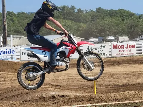 A person rides a dirt bike on a dirt track.
