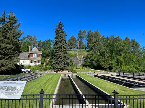 An outdoor view of historical raceways with a building and trees in the background under a clear blue sky.