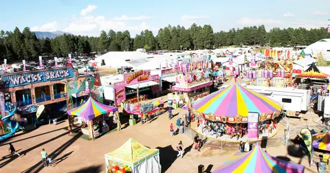An overhead view of an outdoor carnival with colorful tents and rides.