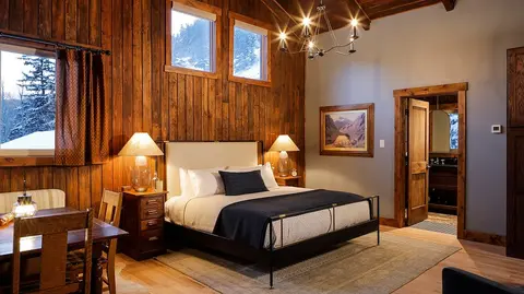 A rustic bedroom with wood paneling and a large bed.