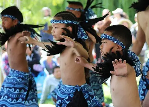 Children performing a traditional dance wearing blue patterned headbands and skirts.