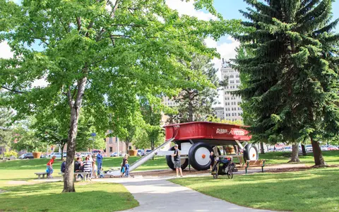 A large red wagon structure with a slide in a park.
