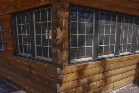 An exterior corner view of a log cabin with large multi-pane windows.