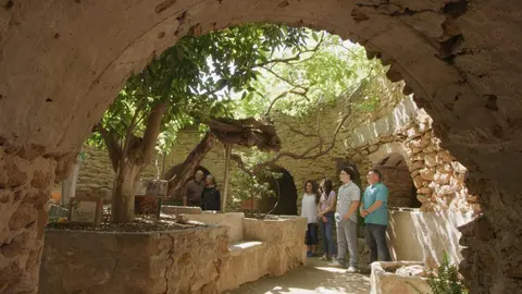 People standing inside a historic stone ruin with trees and foliage.