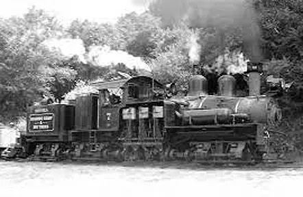 A black and white photograph of a historic steam locomotive outdoors.
