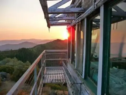 A sunset viewed from the exterior balcony of a lookout tower.