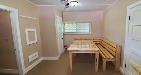 An interior view of a room featuring a wooden dining table and corner bench.