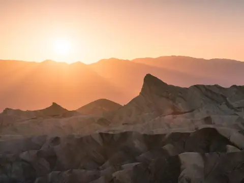 A sunset over rugged rock formations and distant mountains.