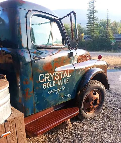 A vintage rusty truck parked outdoors with lettering on the side.