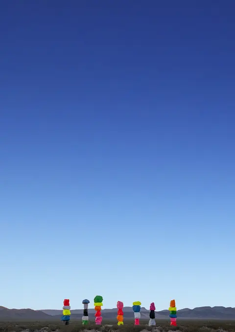 A row of brightly painted rock towers stands under a clear blue sky.