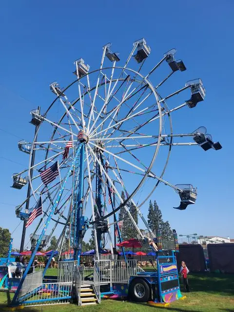 A ferris wheel stands outdoors against a blue sky.