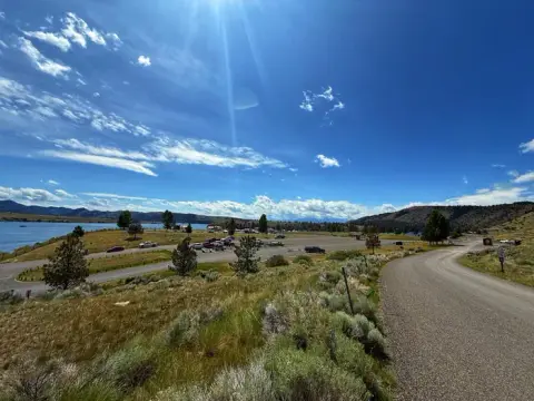 A view of a road and a parking area near a lake under a bright blue sky.