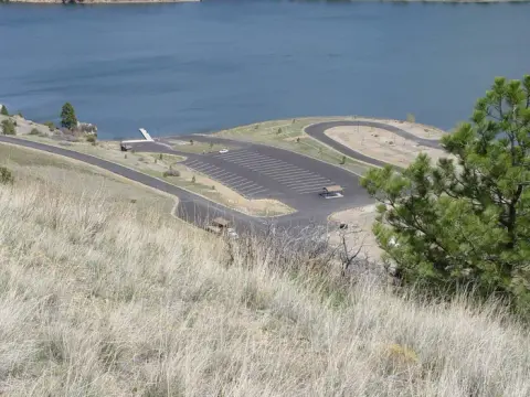 An elevated view of a parking lot and boat ramp next to a body of water.