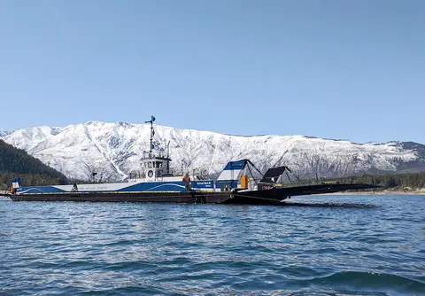 A ferry on the water with snow-covered mountains in the background.