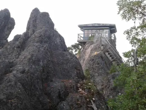 A fire lookout tower sits atop a rocky outcropping.