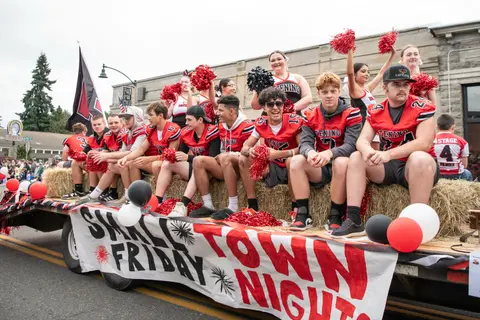 A group of students on a parade float with a banner.