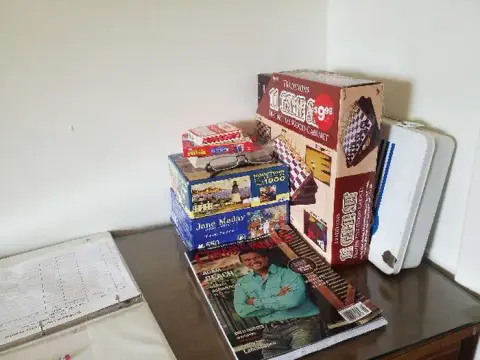 A stack of board games and a magazine on a table indoors.