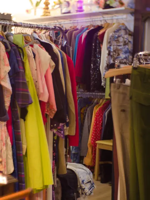Clothing hangs on racks inside a shop.