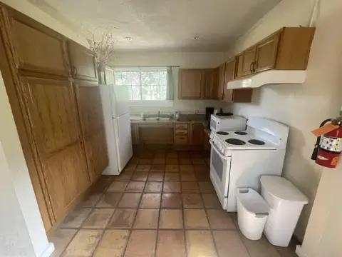 A kitchen with wooden cabinets, tile flooring, and white appliances.