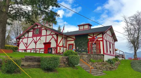 Exterior view of a building with half-timbered red and white walls on a grassy slope.