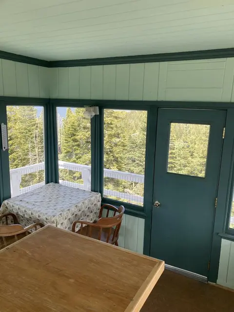An interior view of a room with windows looking out onto a forest.