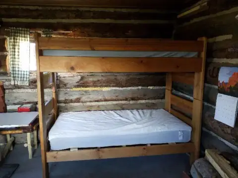A wooden bunk bed inside a rustic log cabin.