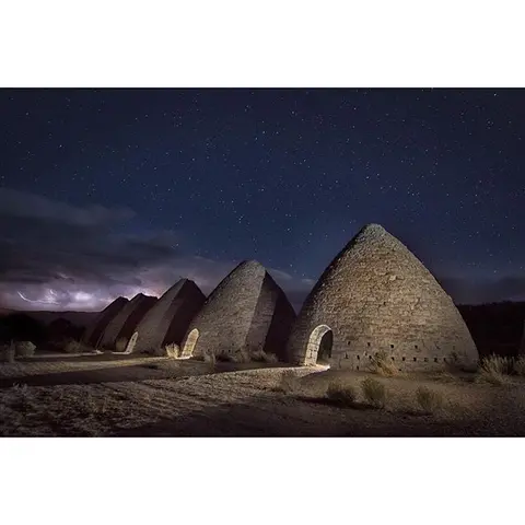 Stone beehive kilns stand under a starry night sky.