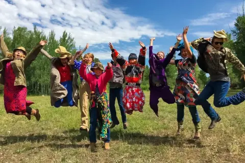 A group of people in costumes jump in the air outdoors.