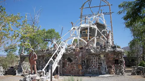 A unique stone building decorated with white sculptural figures under a clear blue sky.