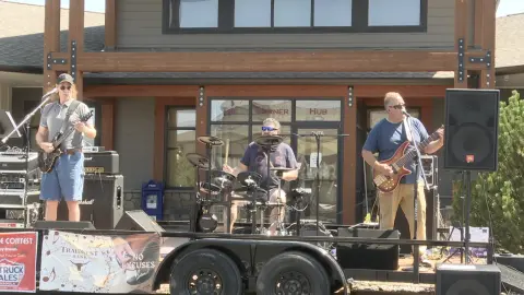 A band performs on a trailer stage outside a building.