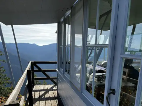 A view from the balcony of a lookout tower with mountains in the distance.