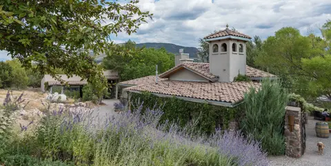 An exterior view of a building with a tiled roof and a tower, surrounded by greenery.