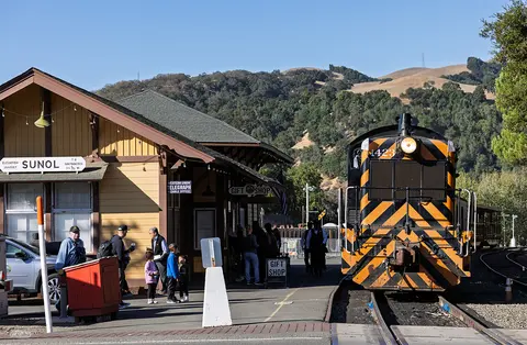 A train sits at a station platform next to a yellow building.