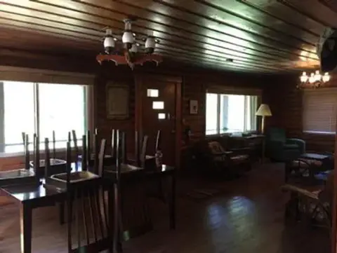 An interior view of a rustic log cabin with wooden walls, ceiling, and furniture.