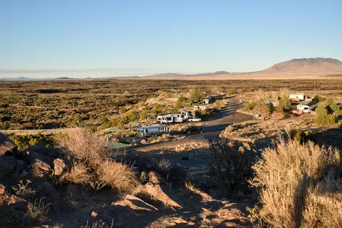 An elevated view of an RV campground set in a desert landscape with mountains in the distance.
