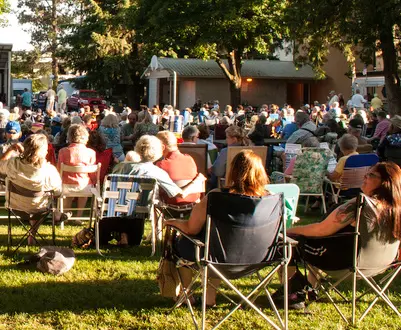 A large crowd of people sitting in lawn chairs outdoors.