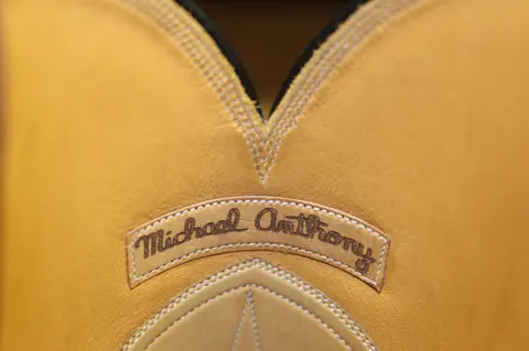 A close-up shot of yellow leather with stitching and embroidered text.