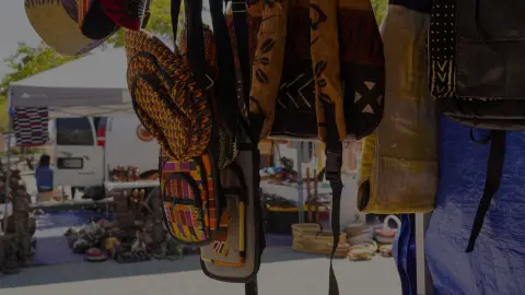 Various bags and textiles hanging at an outdoor market.