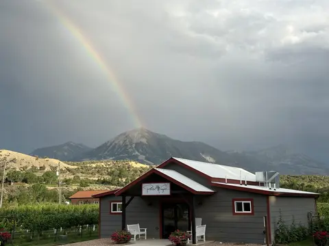 A rainbow appears over a mountain behind a building.