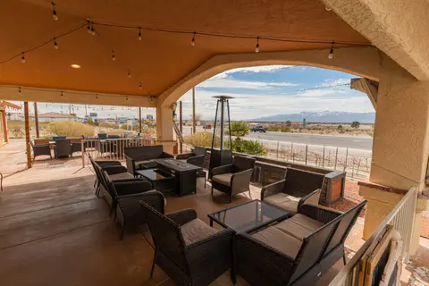 A covered outdoor patio with wicker furniture overlooks a road and distant mountains.