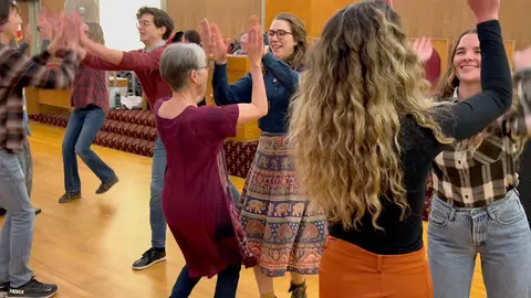 People dancing together in a room with a wooden floor.