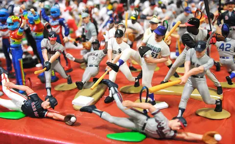 A collection of small baseball figurines displayed on a red surface.