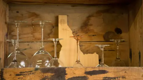 A collection of wine glasses stored upside down in a wooden box.