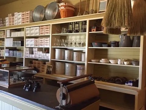 A photograph showing the interior of a historic store with shelves stocked with goods and a counter in the foreground.