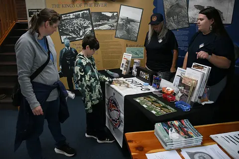 People looking at displays and brochures at an information table indoors.