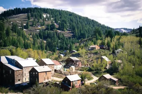An aerial view of a rustic mountain town nestled among forested hills.