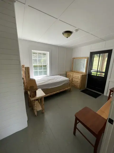 An interior view of a rustic bedroom with a bed and wooden furniture.