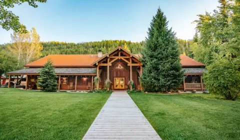 Exterior view of a large wooden lodge with a pathway leading to the entrance.