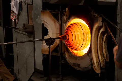 Molten glass is heated inside a glowing furnace.